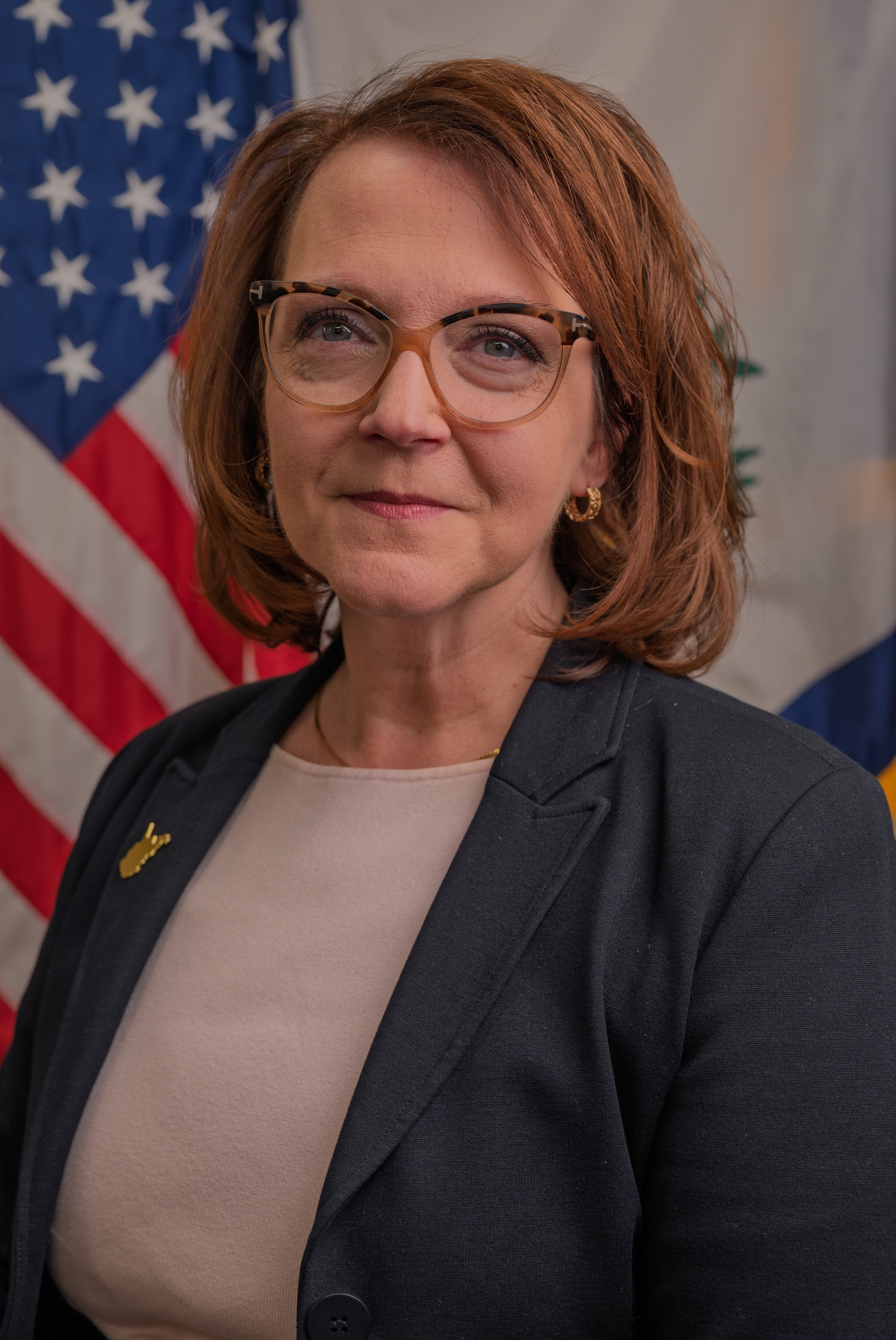 Portrait of Heather Brunton standing in front of American Flag and WV State Flag