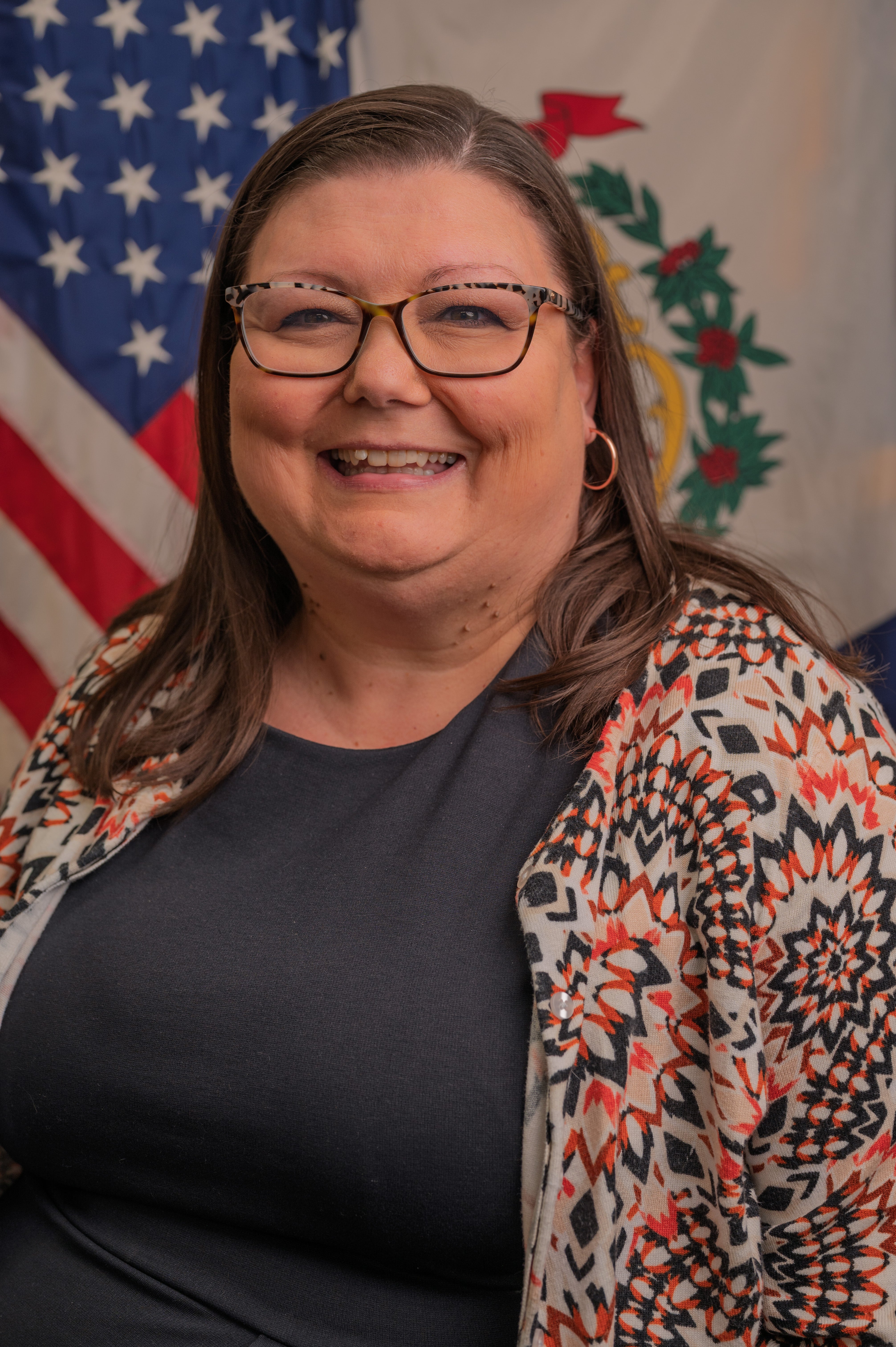 Portrait of Krista Bradshaw standing in front of American Flag and WV State Flag