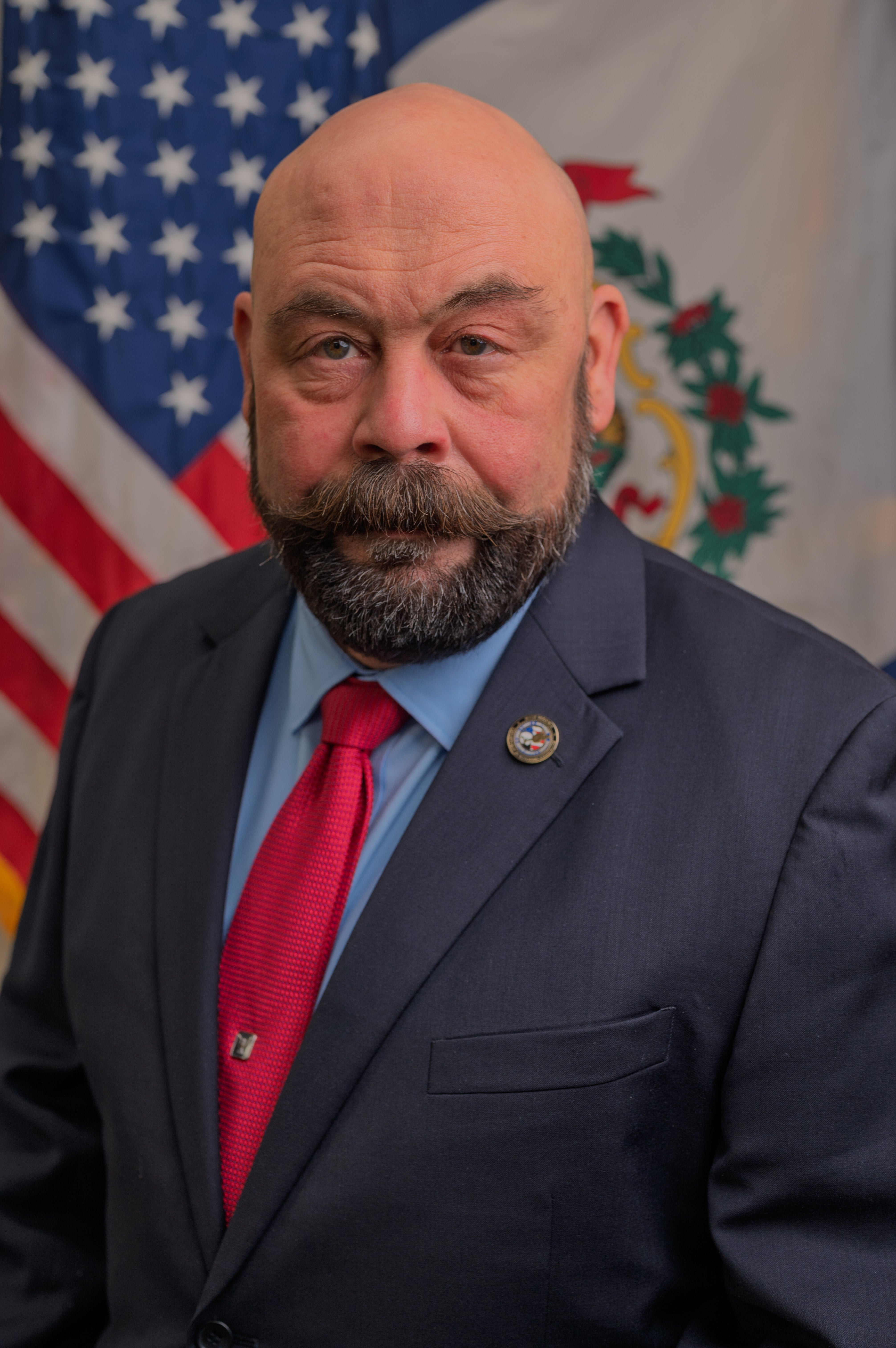 Portrait of Michael Dooley standing in front of American Flag and WV State Flag