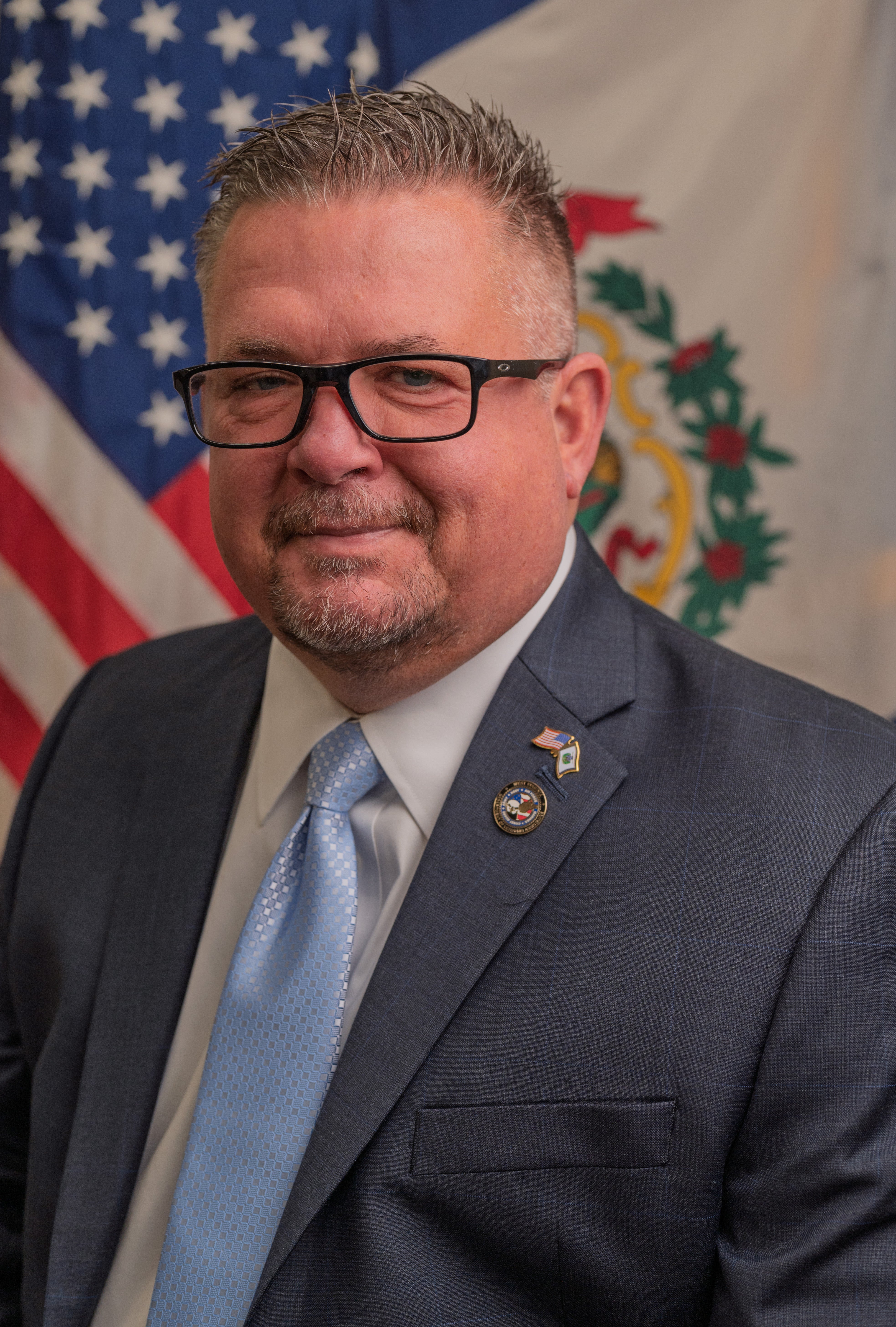 Portrait of Steve Mooney standing in front of American Flag and WV State Flag