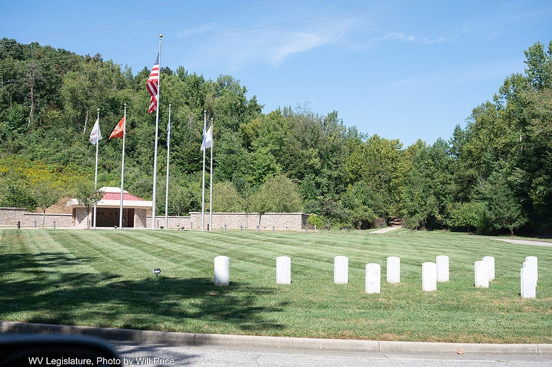 Outdoor photo of headstones in front of flags at the state cemetery